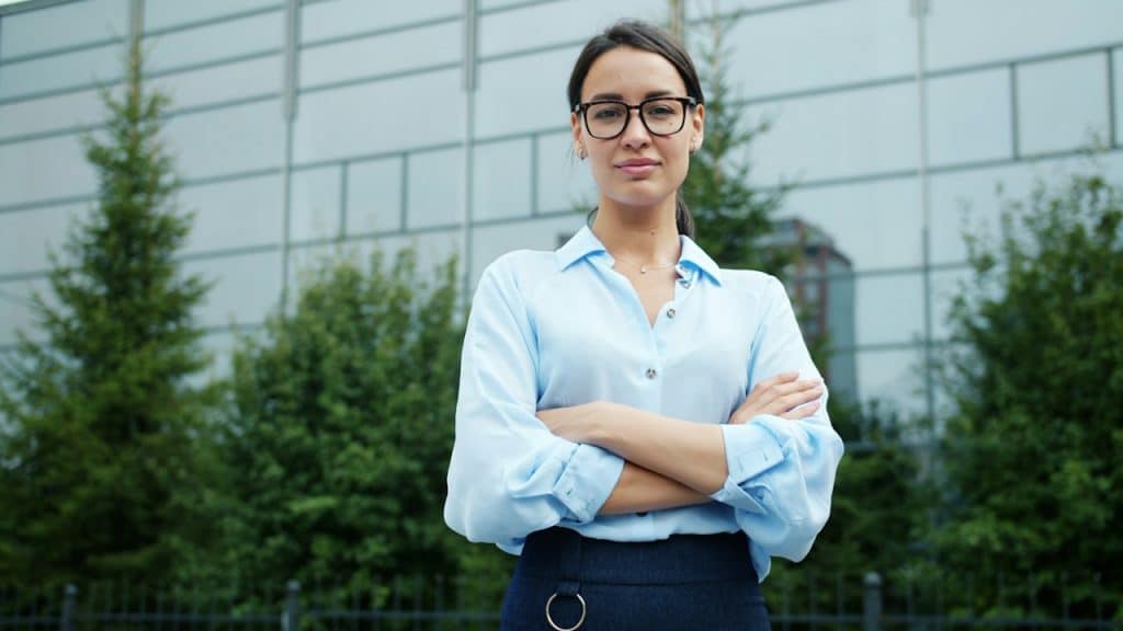 A businesswoman wearing glasses is standing in front of the office.