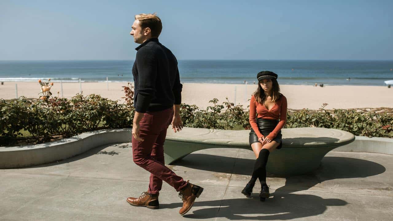A man walking away from his upset girlfriend