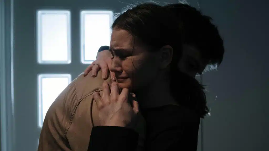 A woman crying while hugging someone for comfort.