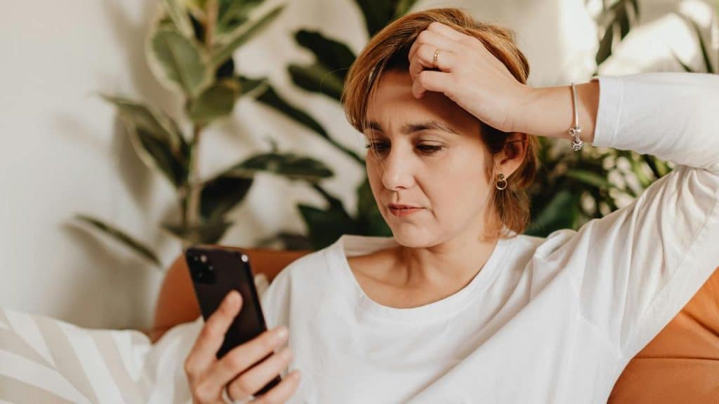 A woman looking at her phone with a concerned expression.