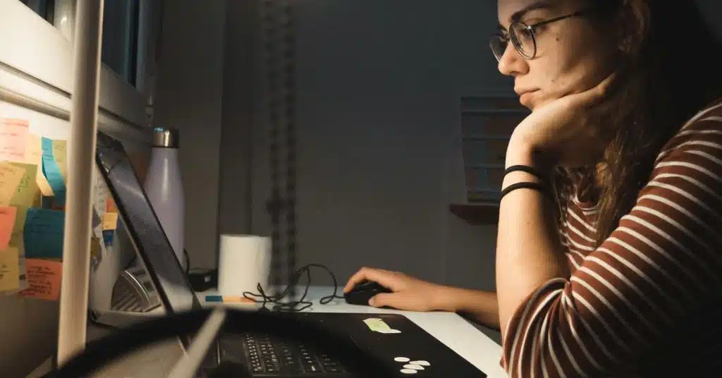 A woman concentrating while working on a laptop at a desk.