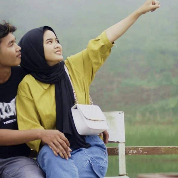 A couple sitting on a bench in nature.