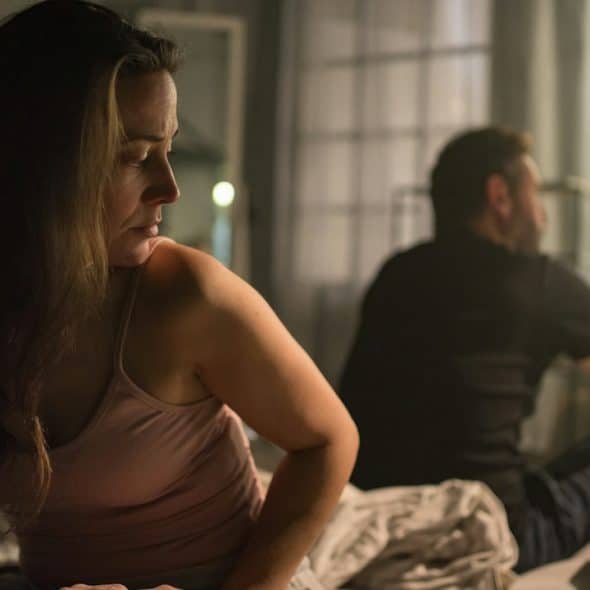 An unhappy couple sitting on the bed after a fight.