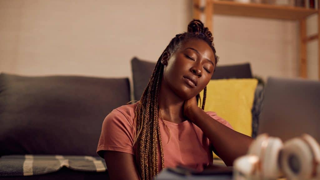 A tired woman with her hand on her neck.
