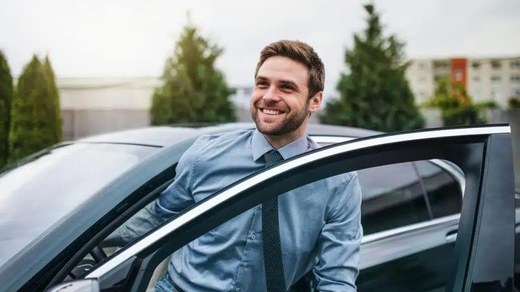 A man smiling while getting out of a car.