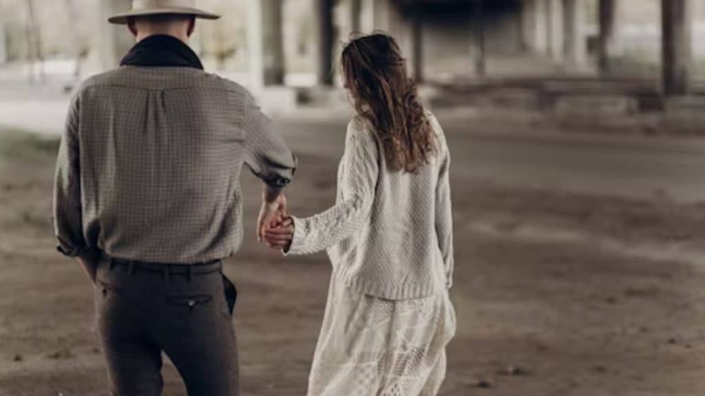 Man looking distant while woman reaches for his hand
