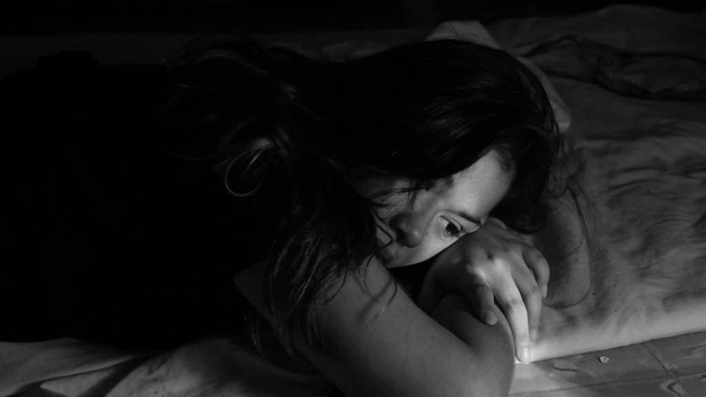 A sad woman is lying on the bed.