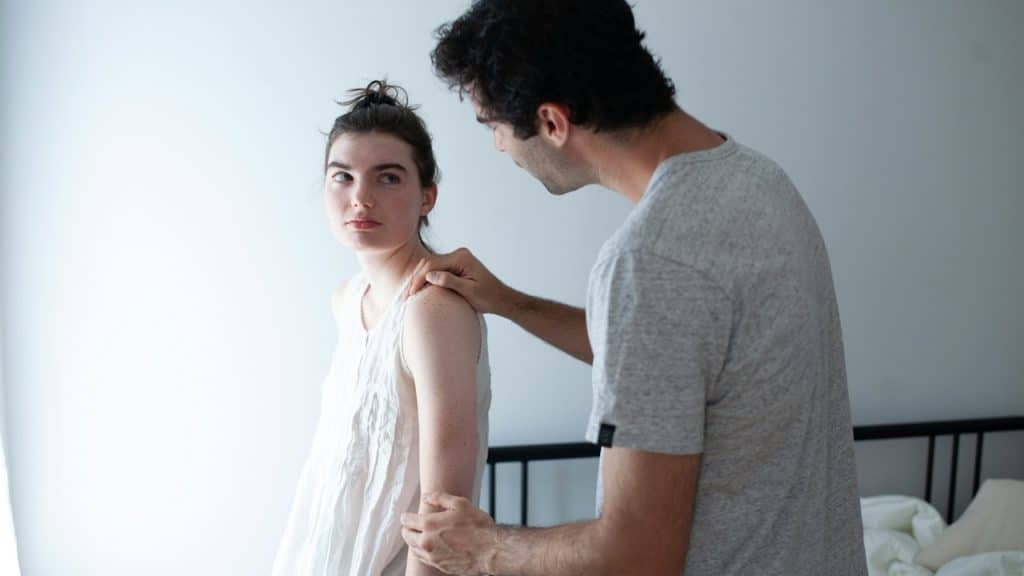 A man holding his wife’s arm in order to reconcile after a fight.