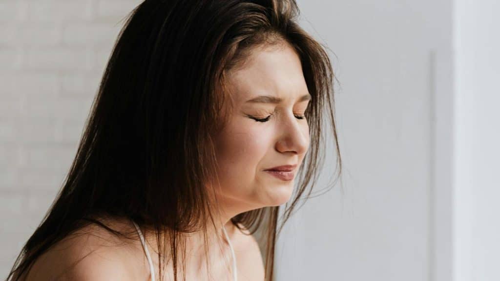 A woman with her eyes closed looking stressed or upset.