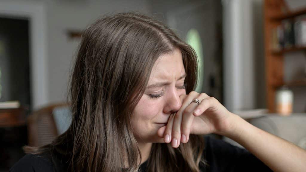 A crying woman wiping her nose with her hand.
