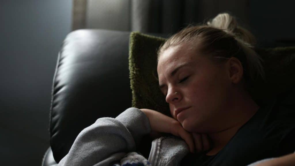 A woman sleeping peacefully on a couch with her head resting on her hand.
