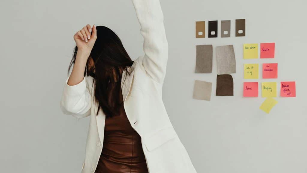 A woman dancing joyfully indoors with one arm raised.