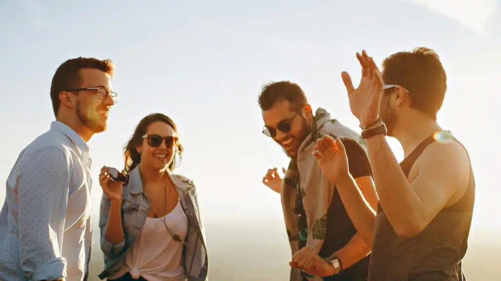 A group of friends laughing and enjoying time together outdoors at sunset.