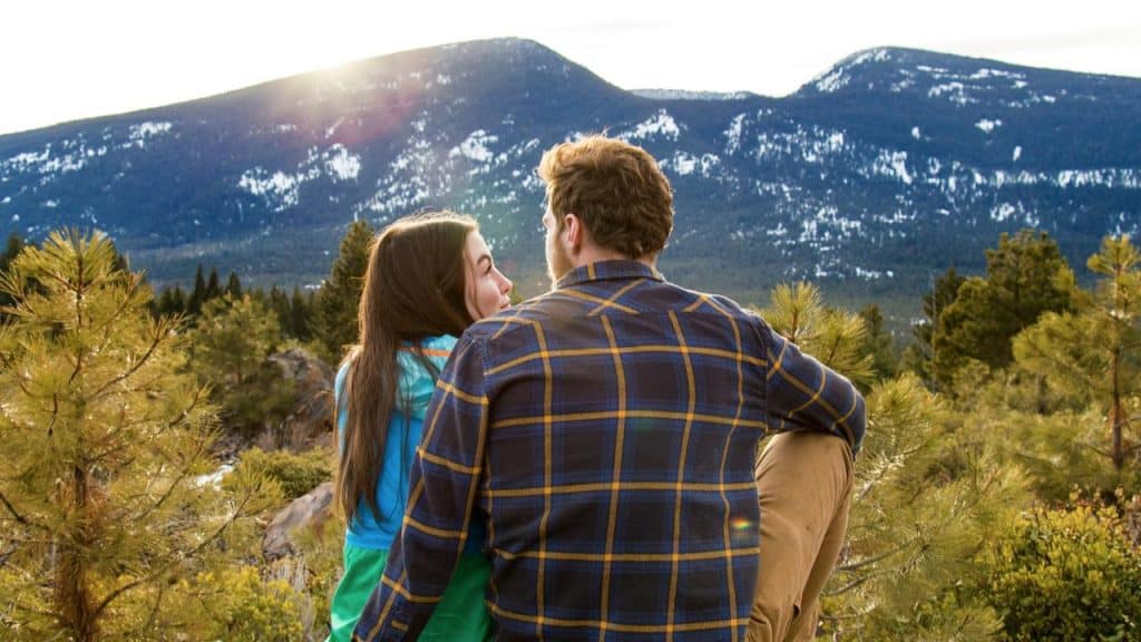 A couple sitting together and looking out over a mountain landscape.