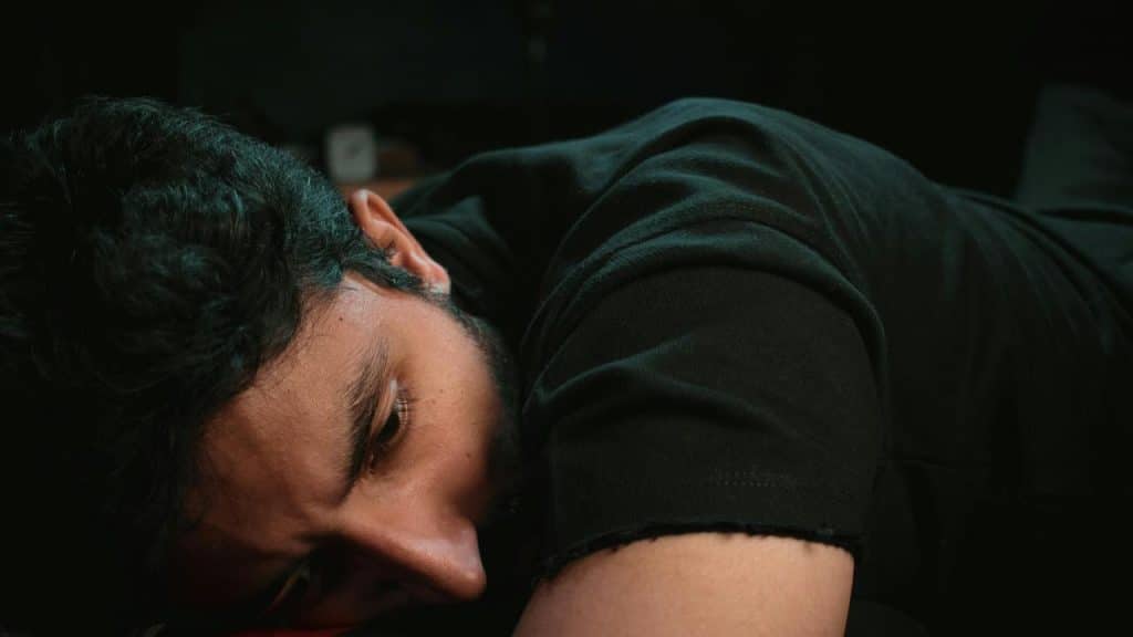 A person lying on their side with a sad, tired expression.