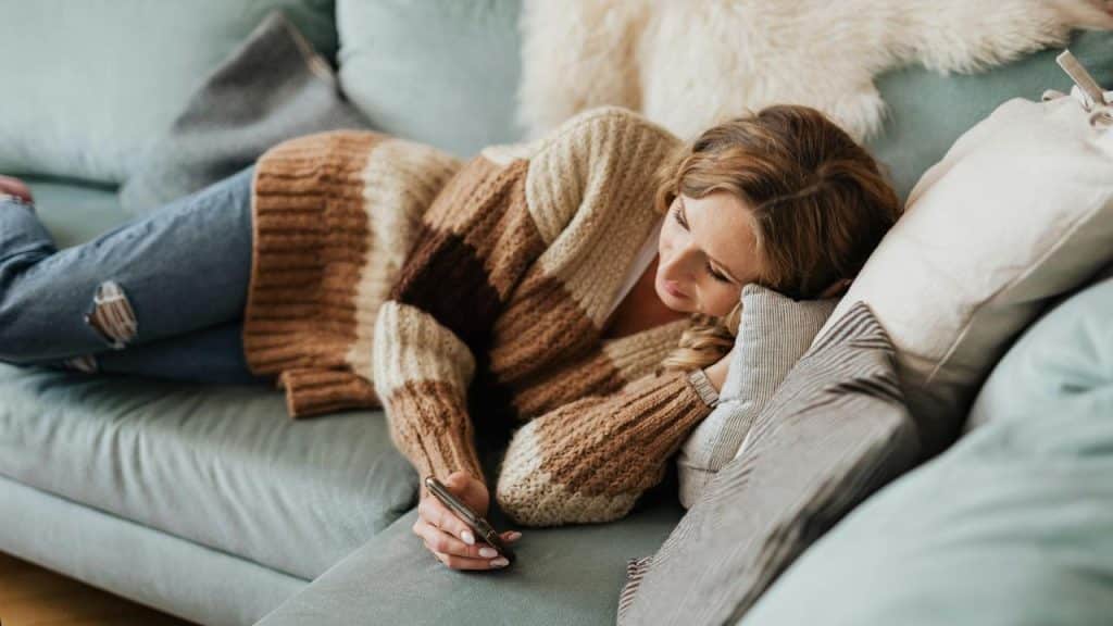 A woman lying on a couch holding a phone.