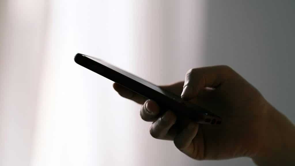 A person’s hand holding a smartphone with the screen facing up.