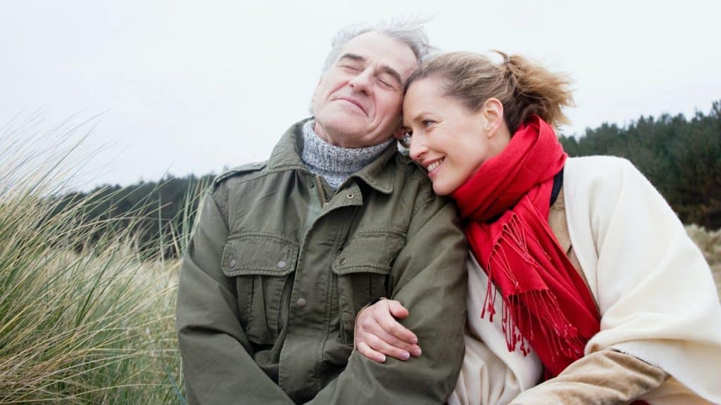 A man and a woman sitting on a bench together.