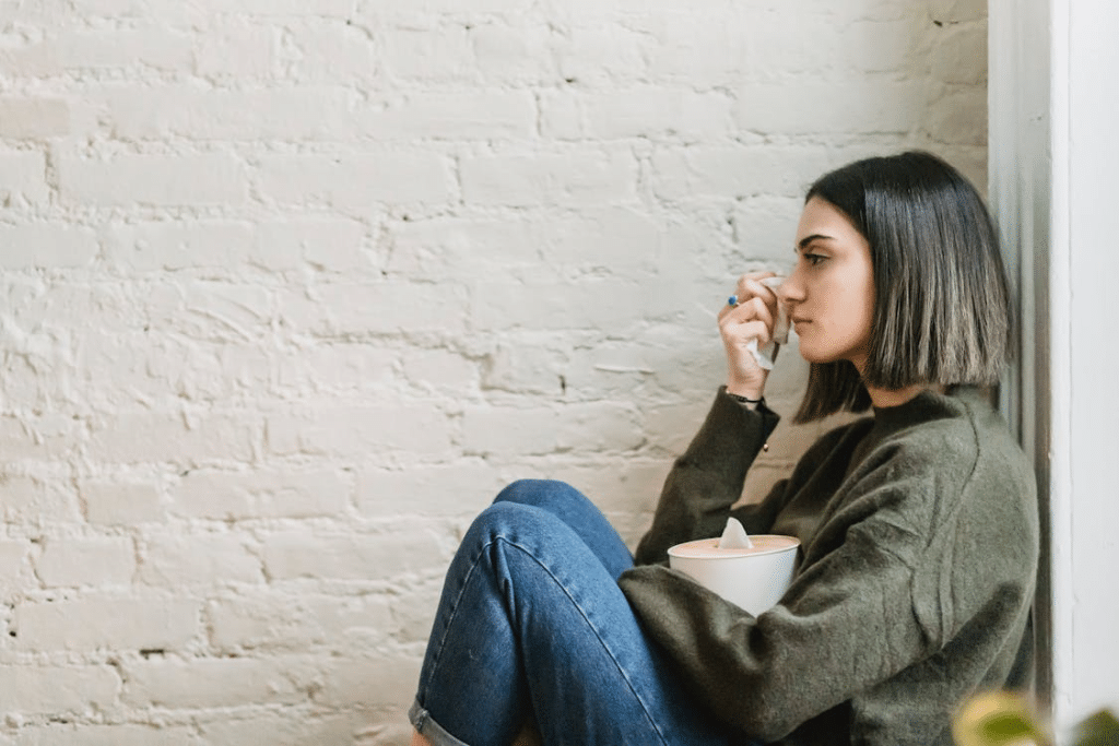 Young woman crying sitting against the wall
