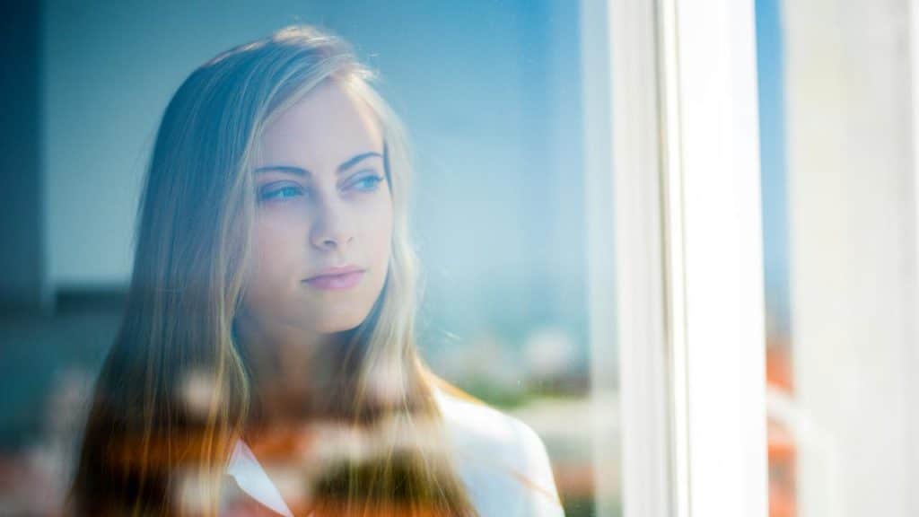 A young woman gazing out a window with a thoughtful expression.