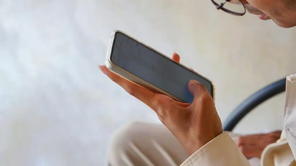 A person holding a smartphone and looking at the screen.
