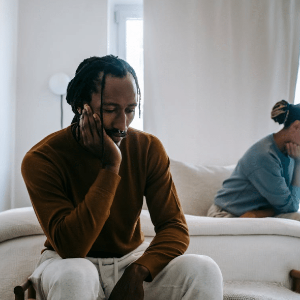 Upset black couple sitting apart at home