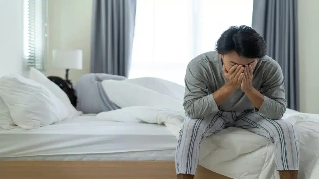 A man looking upset while his wife sleeps