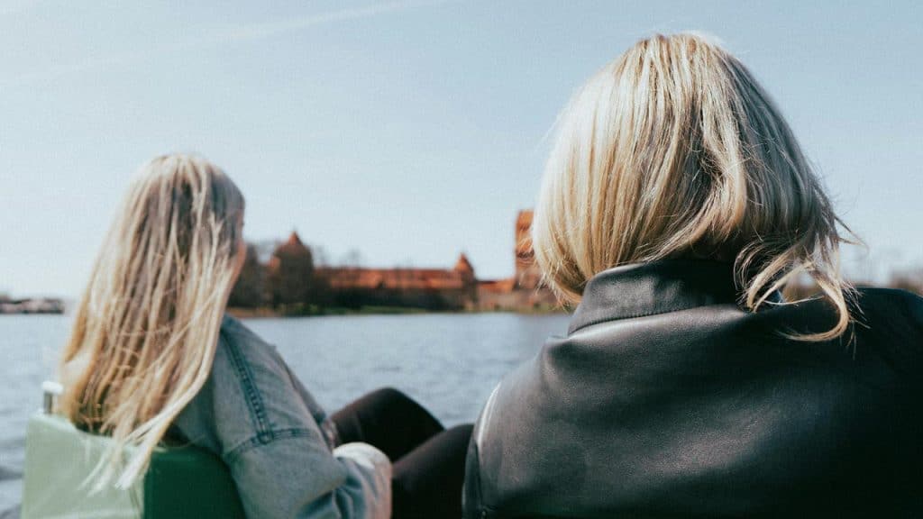 A pair of women sitting by the water and enjoying the view.