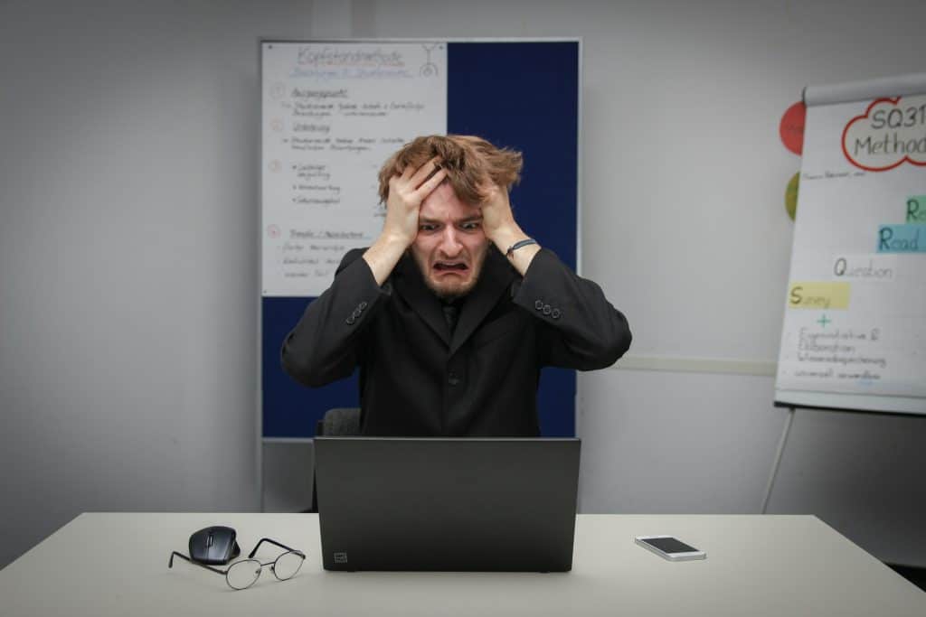 Alt text: stressed man holding head