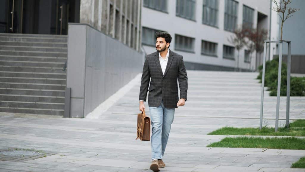 A man holding a bag is walking on a street.