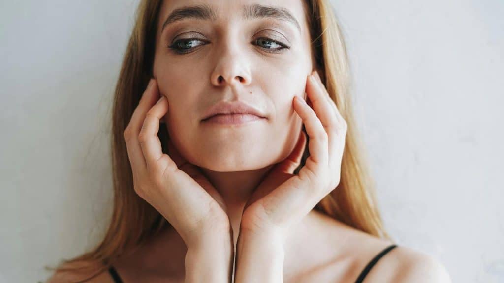 A woman resting her hands against her face while looking ahead.