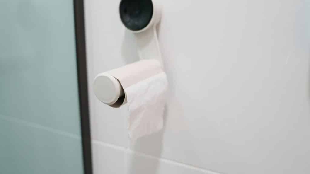 A toilet paper roll partially unspooled on a bathroom wall holder.