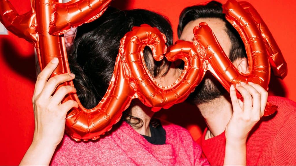 A man and woman holding a balloon that spells ‘love’