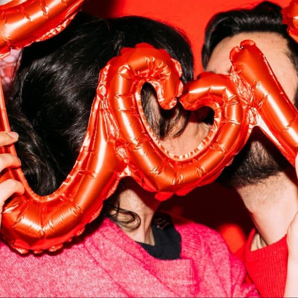 A man and woman holding a balloon that spells ‘love’