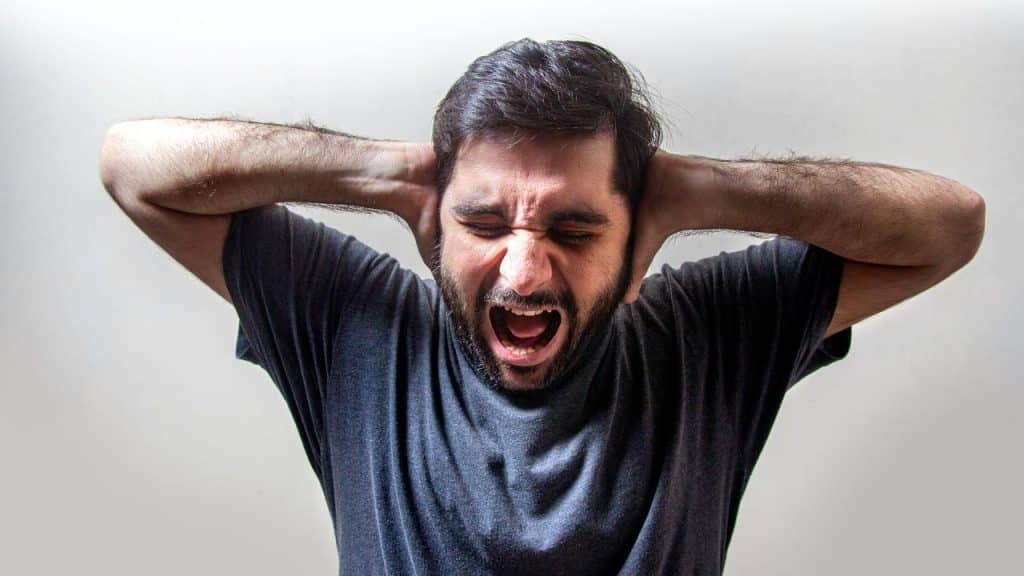 A man yawning with his eyes closed and hands behind his head.