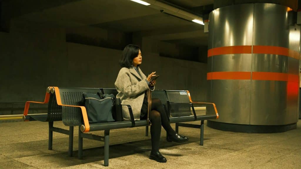 A woman sitting on a bench using a cell phone.