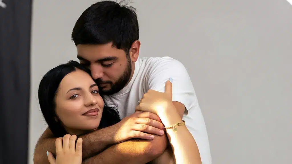 A man hugging his wife from behind.