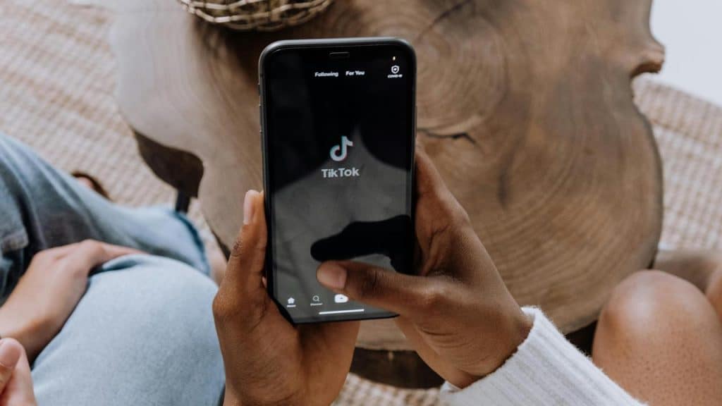 A person holding a phone with the TikTok app open.