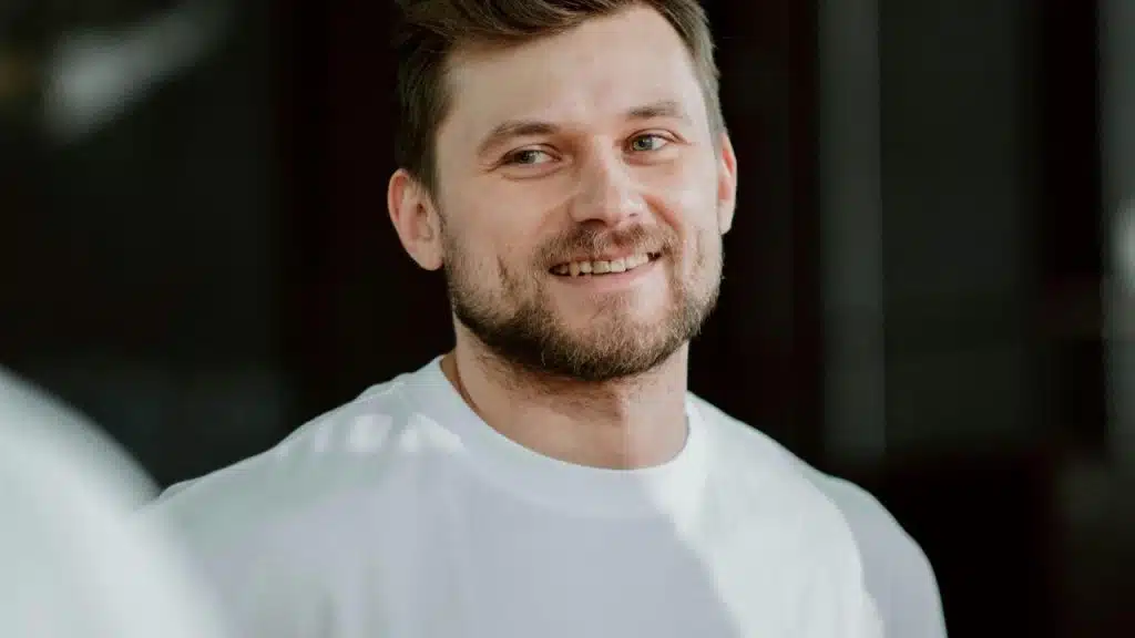 A man smiles while looking to the side.