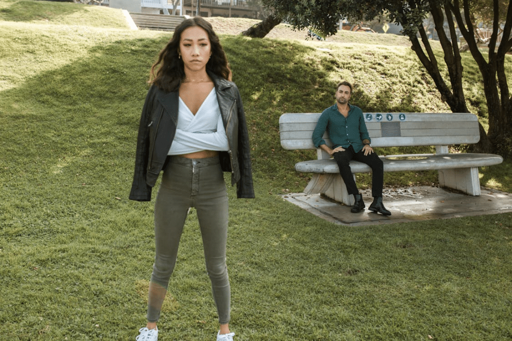 A Man Sitting on a Bench while Looking at Upset Woman