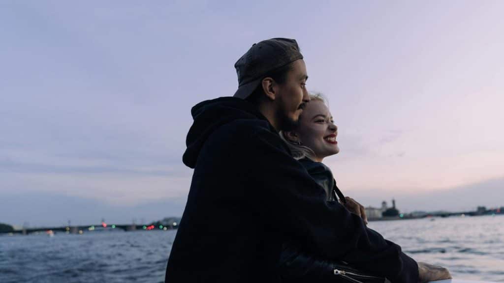 A couple embracing by the water at dusk.