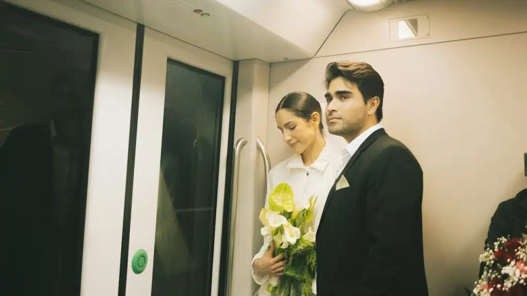 A couple wearing formal clothes, woman holding flowers are travelling on a train.