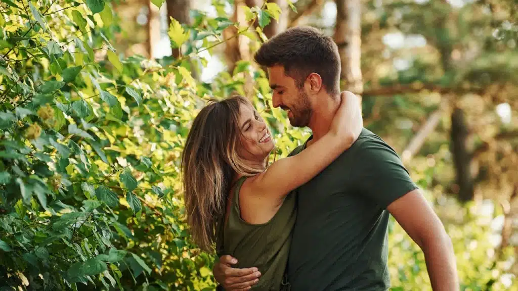 A man and a woman hugging each other outdoors.
