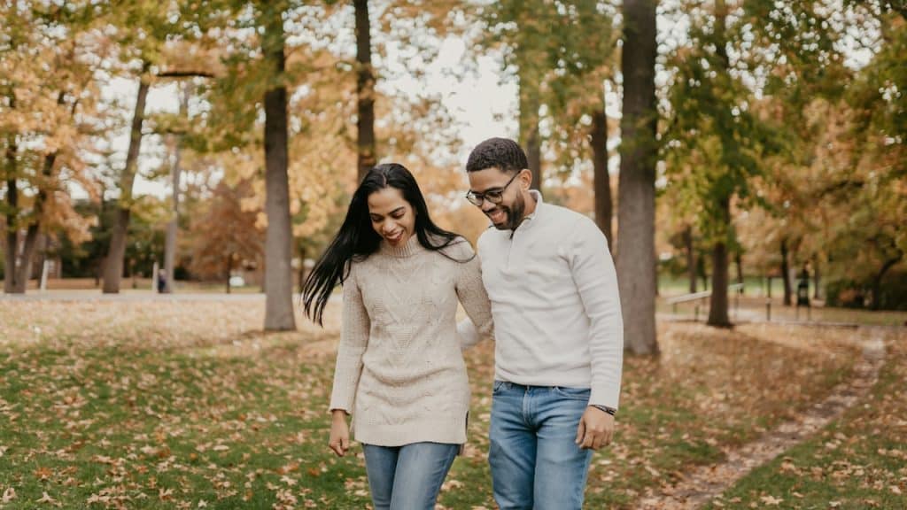 A couple walking through a park and smiling.