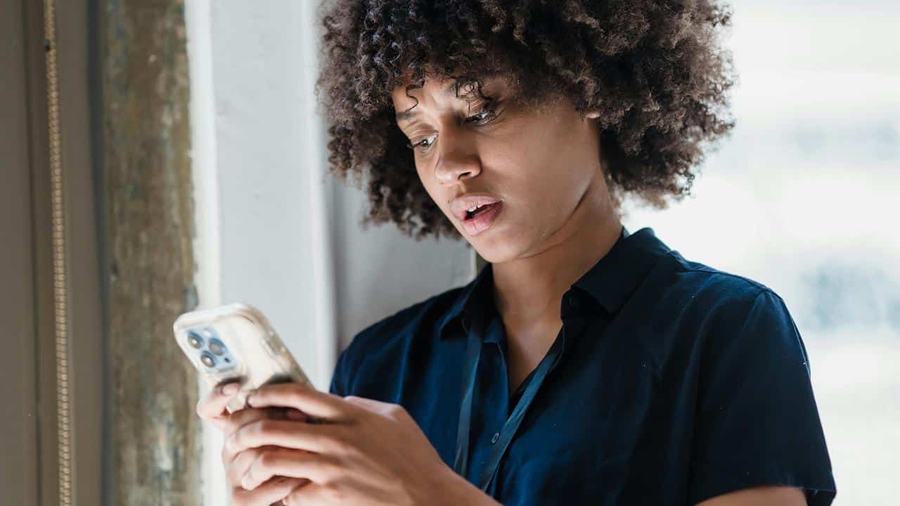 A woman looking at her phone with a concerned expression.