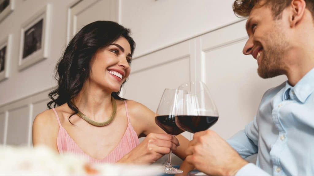 A man and woman toasting glasses together 