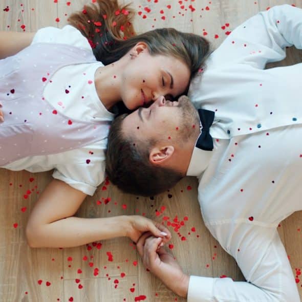 A couple lying on the floor with rose petals.
