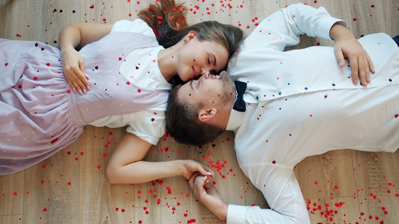 A couple lying on the floor with rose petals.