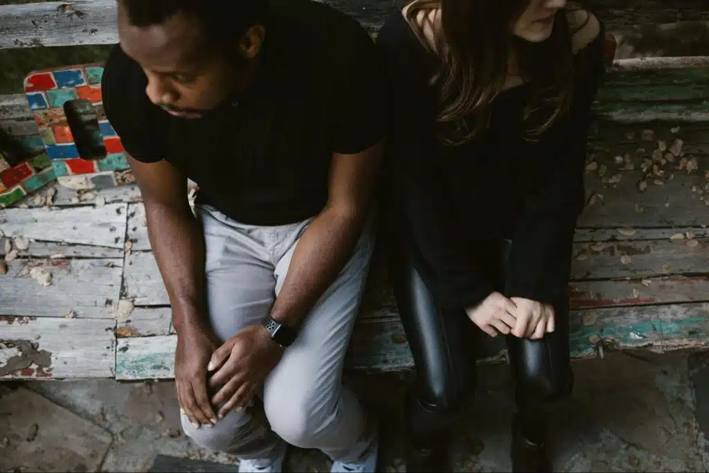 A man and woman sitting at the wooden bench