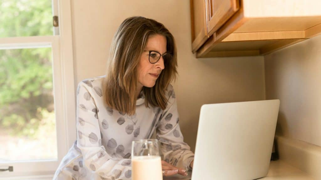 A bespectacled mature woman using a laptop.